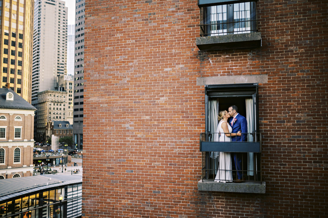 Bride and groom kissing at the balcony at the Bostonian Hotel