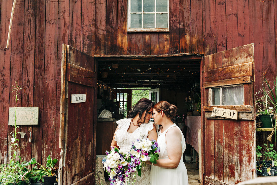 Brides kissing in barn at Hartmans Herb Farm