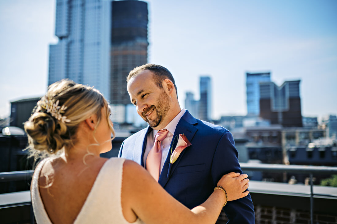 Groom smiling at bride during their first look on the roof of the Bostonian