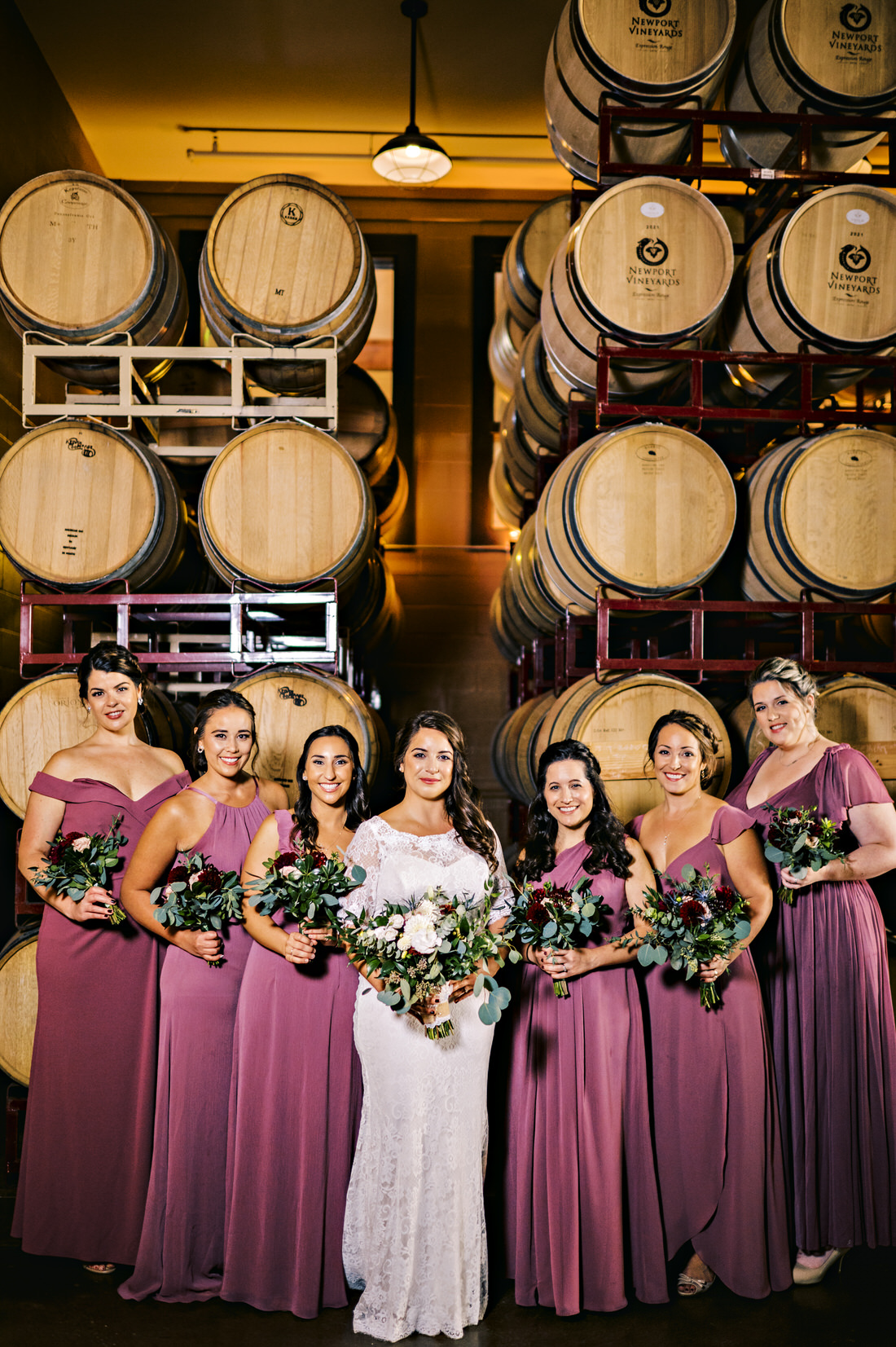 Bridesmaids posing in front of wine barrels