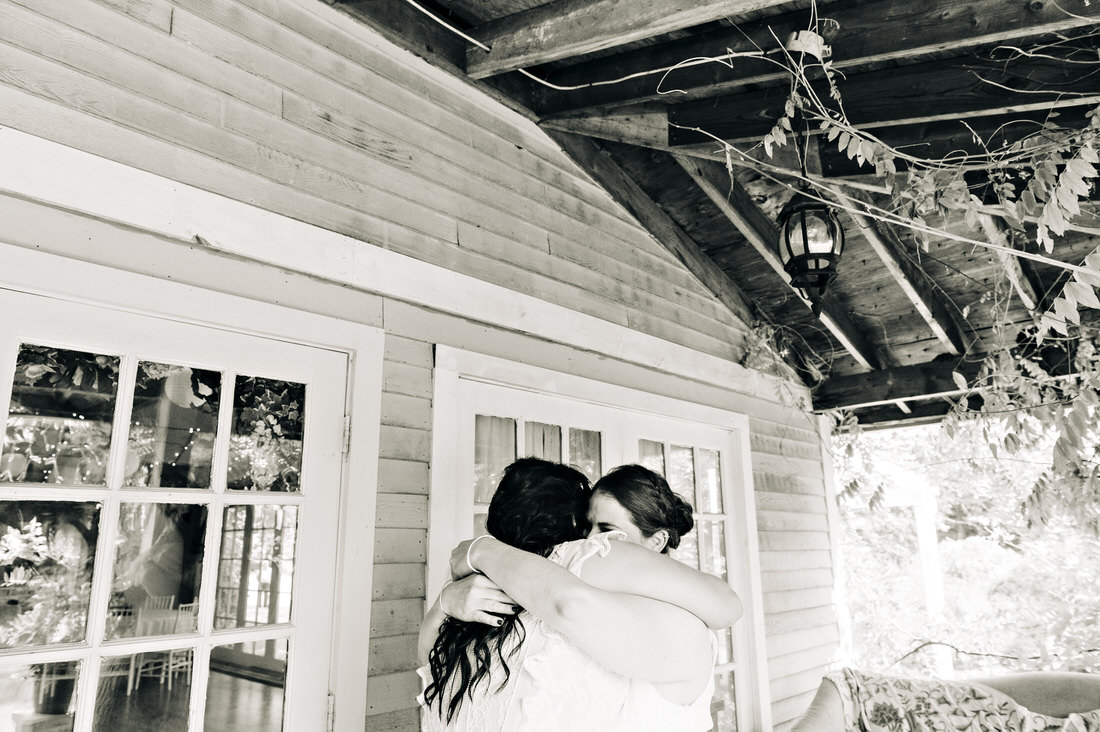 Black and white photo of brides hugging at their first look