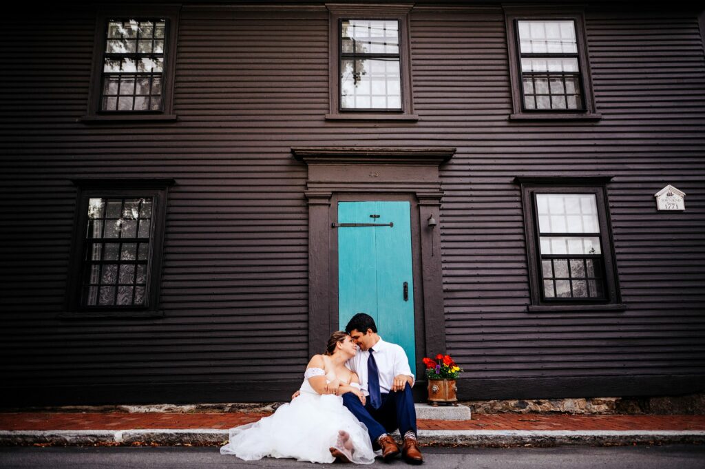 Bride and groom sitting in front of blue Salem door