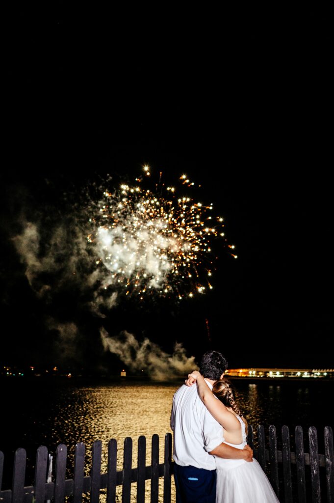 Bride and groom watching fireworks over Salem Harbor 