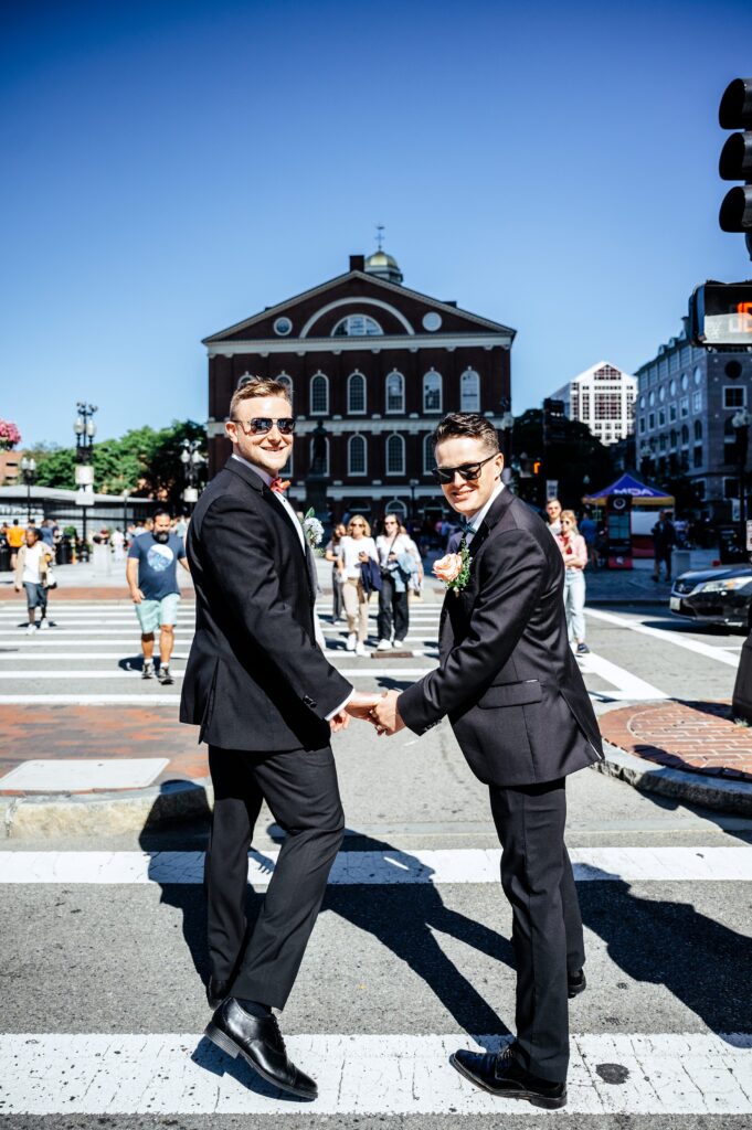 Grooms holding hands walking to Quincy Market on wedding day 