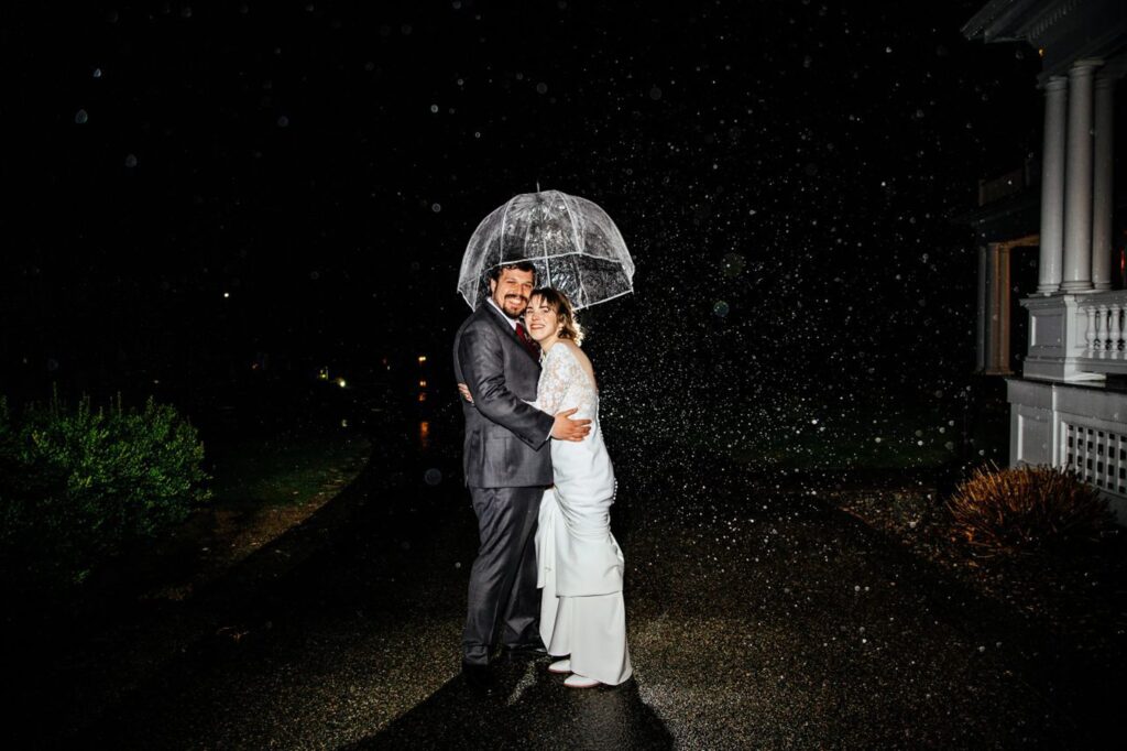 Wedding photo of bride and groom under umbrella 