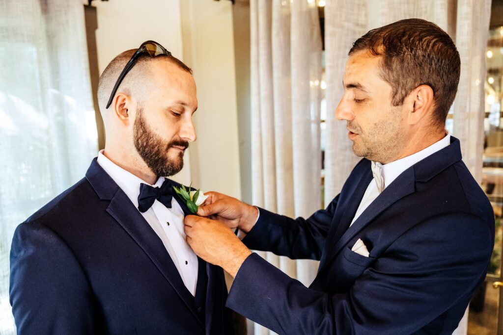 Groom getting help putting on boutonniere 