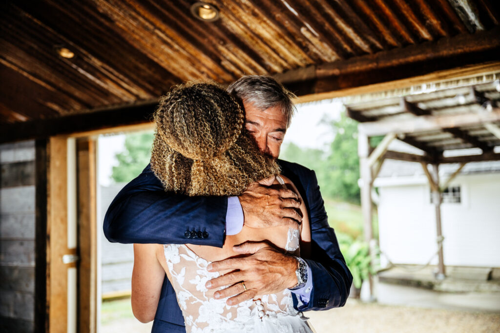 Bride and her father hugging during their first look in the Barn at South Farms