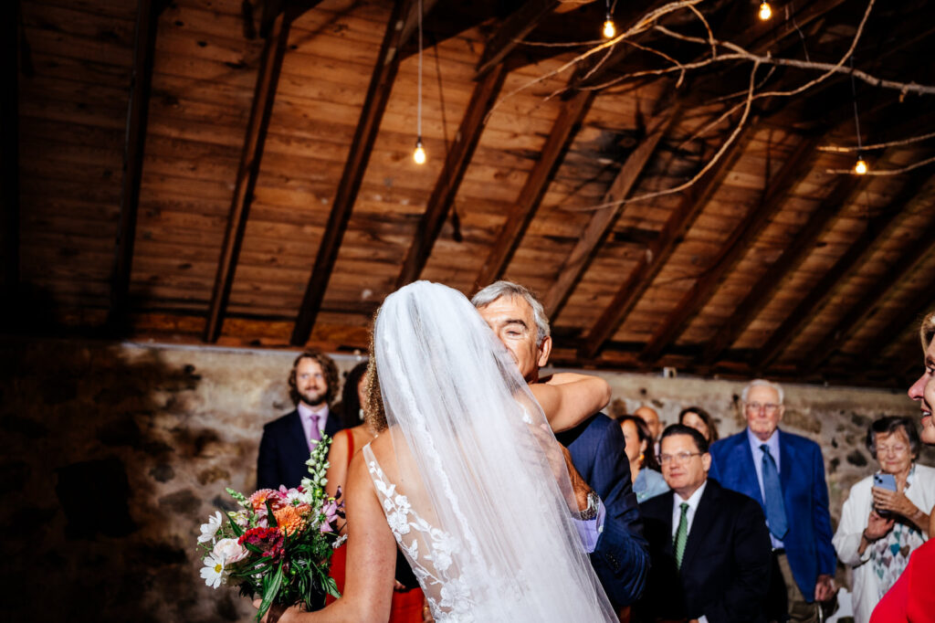 Father of the bride kissing his daughter at the end of the aisle