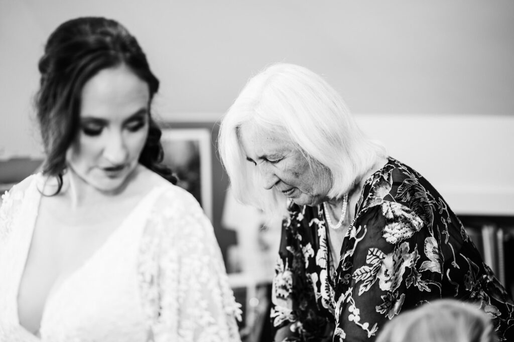 Bride's mother helping her into her wedding dress
